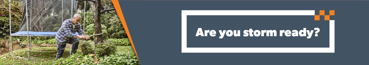 Image showes a man tightens a trampoline, highlighting the need to prepare for storms and ensure safety during severe weather.