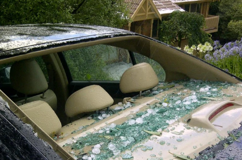 A vehicle featuring a cracked windshield, with shattered glass reflecting the aftermath of a storm.
